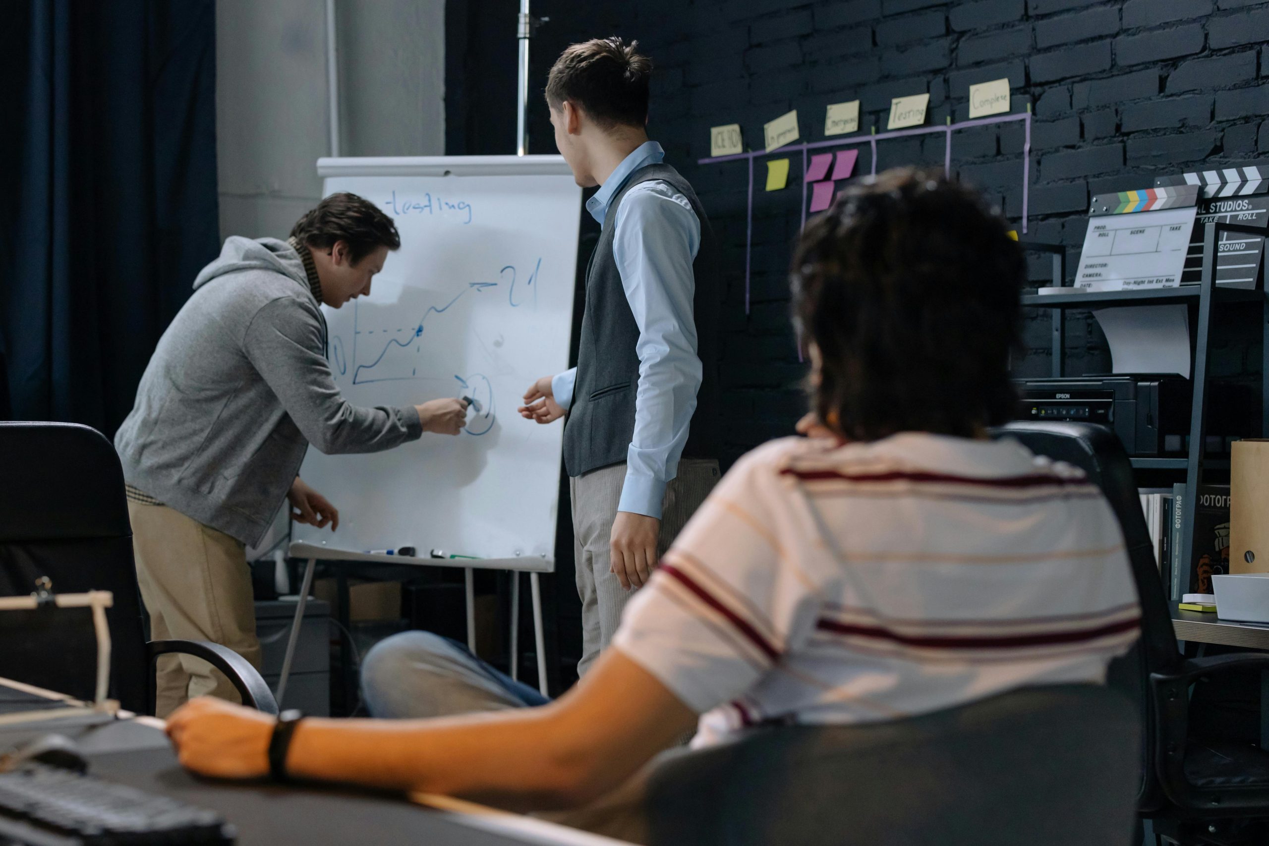 A team brainstorming mobile app concepts on a whiteboard with wireframes and feature lists.